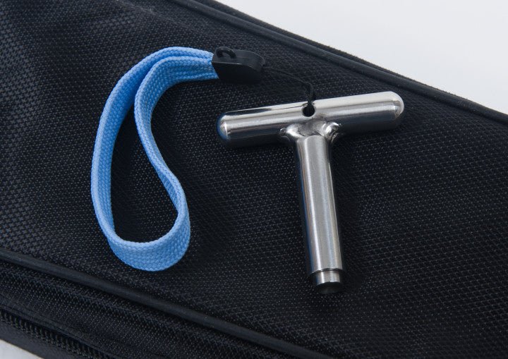 T-förmiger Steckschlüssel aus Edelstahl mit blauem Trageband auf schwarzem Stoffhintergrund.