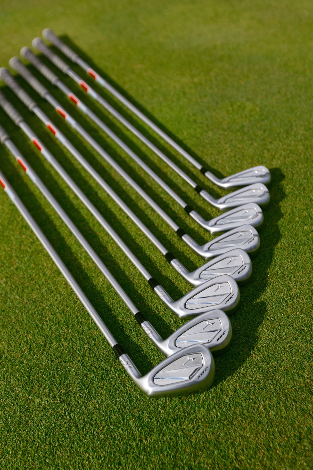 Mizuno JPX 925 Forged Golfschläger Eisen 5PW mit Graphitschaft und silbernem Kopf, liegend auf grünem Rasen.