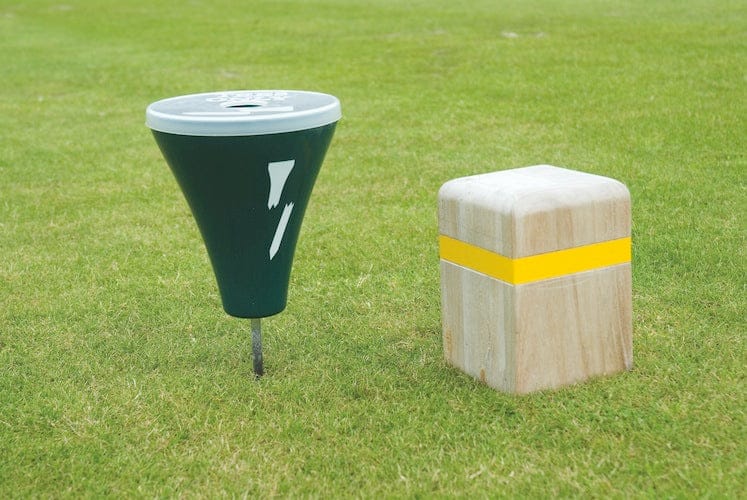 Grüner Kunststoffdeckel für Broken Tee Caddy mit Schlitz, auf Golfplatzrasen neben Holzmarker mit gelbem Streifen.