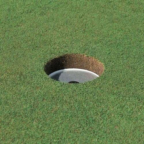 Golfloch mit sauber geschnittenem Rand und silberner Lochabdeckung auf grünem Rasen.