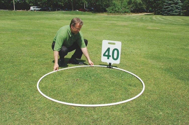 Golf-Entfernungsanzeige mit Zahlen 40 auf grünem Rasen, Mann positioniert weißen Kreis.