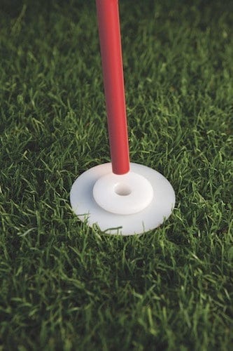 Rotes Stabende im weißen Kunststofffuß auf grünem Rasen beim Golfplatz.