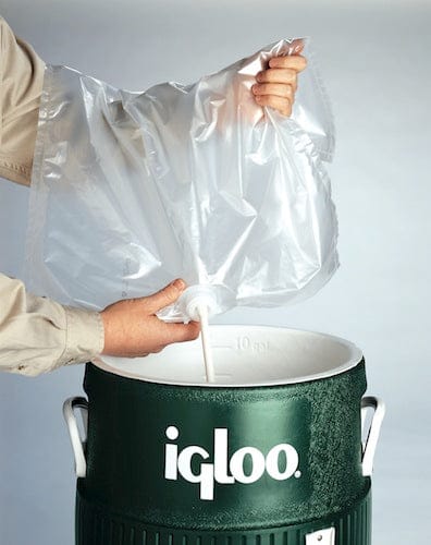 Grüner Igloo Kübel mit weißem Deckel und transparentem Wasserbeutel, der von Händen gehalten wird.