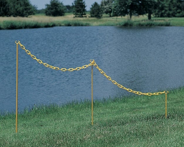 Gelber Metallpfosten mit Kette auf Grasfläche an Wasserufer, 91,5 cm hoch.