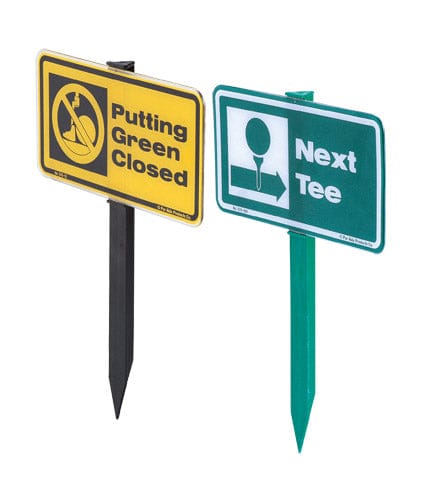 Gelbes Golf-Informationsschild „Putting Green Closed“ mit schwarzem Pfahl neben grünem "Next Tee"-Schild.