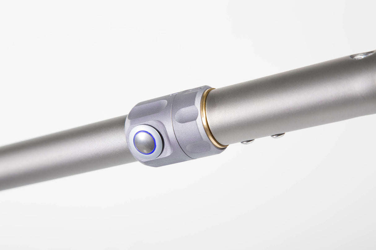 Silberner Golftrolley-Achsstab mit blau beleuchtetem Knopf und titanfarbener Akzentierung.