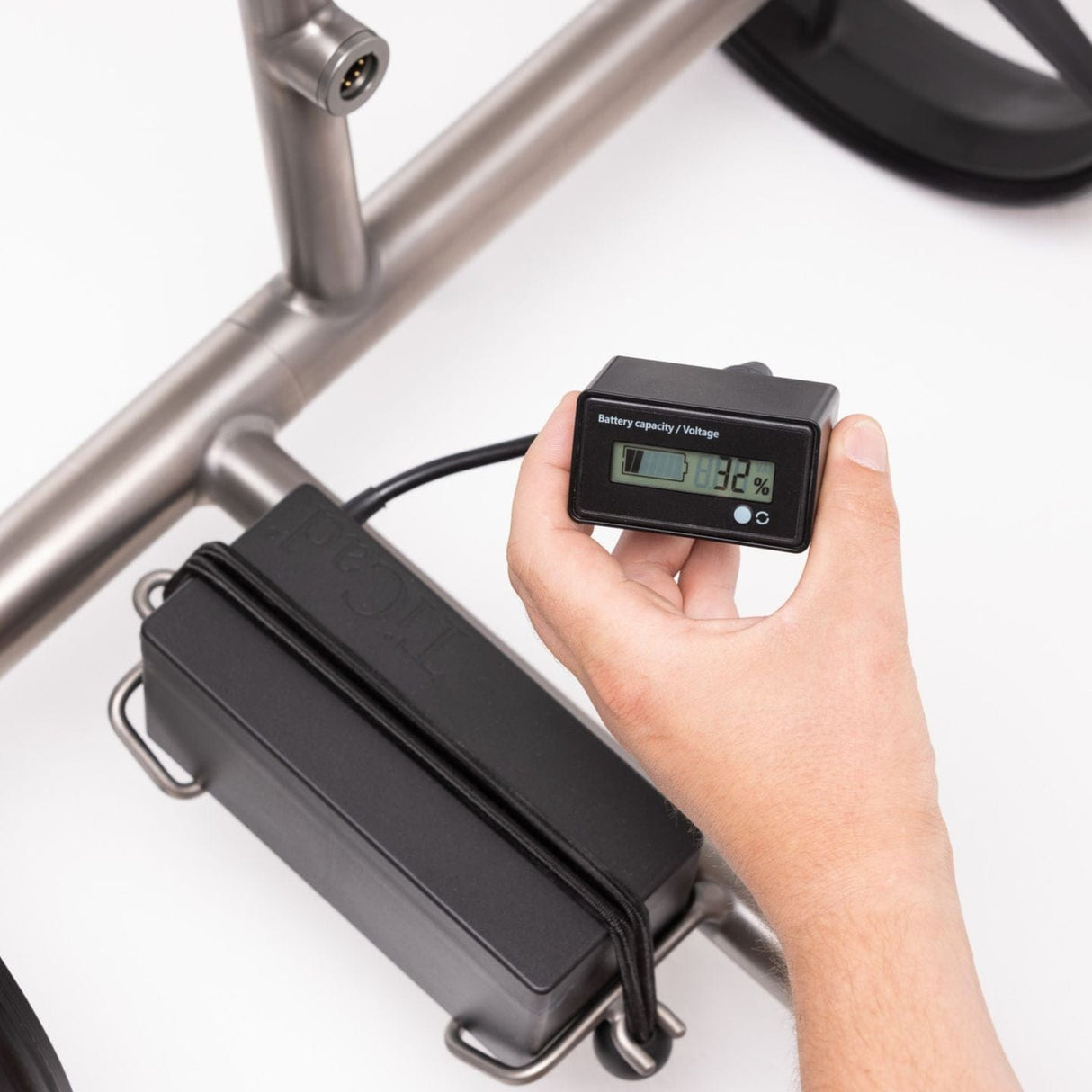 Ticad Battery Checker mit Display, handgehalten, zeigt Akkustand für 4-polige Akkus, angeschlossen an schwarzen Akkuhalter.