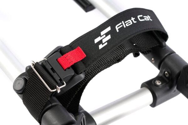 Schwarzer magnetischer FLAT CAT Taschenhalter Riemen aus Nylon mit weißen Logos und rotem Laschelement am Golf-Trolley Rahmen.