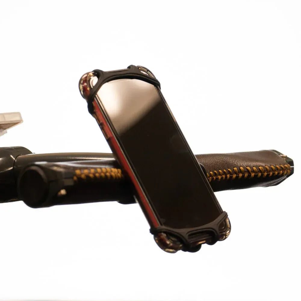 Schwarze Silikon-Smartphone-Halterung mit verstärkten Ecken, umgeben ein rotes Handy auf einem Schwertgriff.