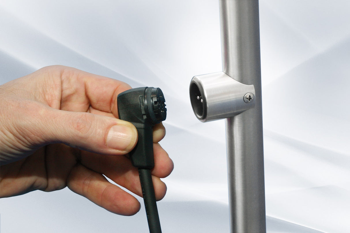 Hand verbindet schwarzen Stecker mit silbernem Metallrohr des Elektrotrolleys.