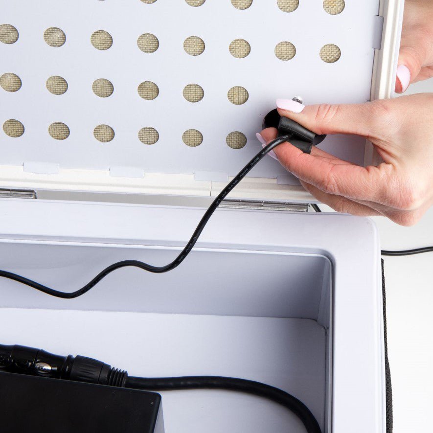 Weiße Akku Lade-Box mit schwarzem Ladekabel und Hand, die Stecker verbindet.