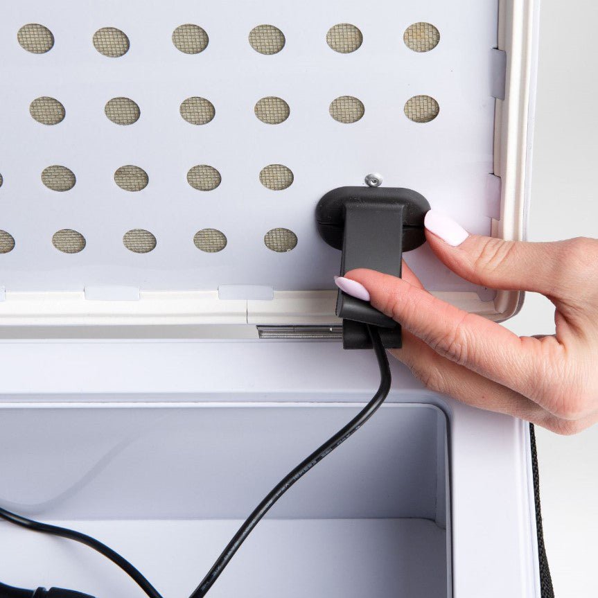 Weiße Trendgolf Watchdog Akku Lade-Box mit offenem Deckel und Hand, die schwarzen Stecker einsteckt.